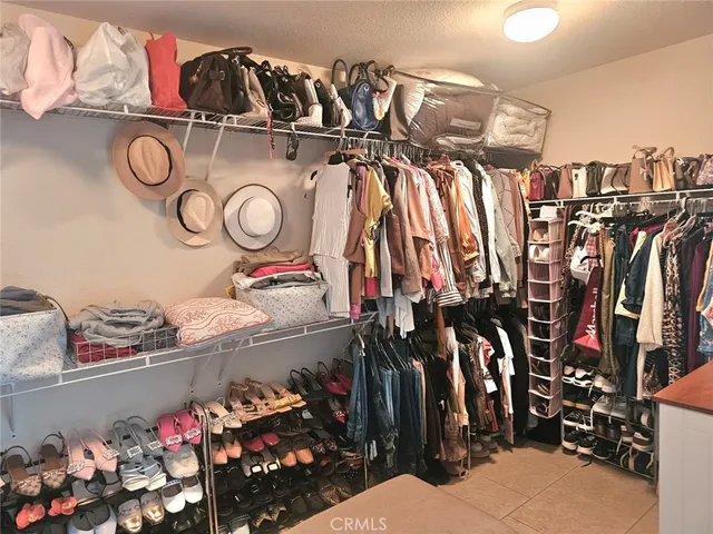 a view of walk in closet with clothes and shoes