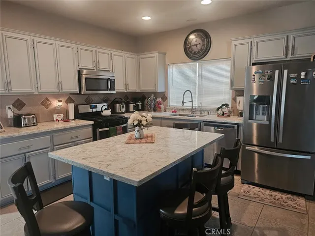 a kitchen with stainless steel appliances granite countertop a sink a stove a refrigerator cabinets and chairs