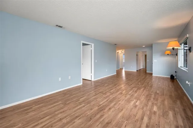 a view of an empty room with window and wooden floor