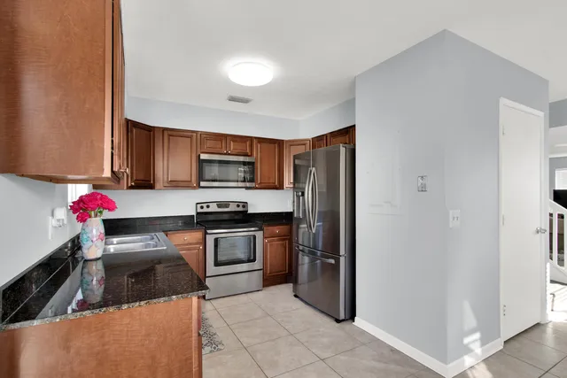 a kitchen with granite countertop stainless steel appliances a stove refrigerator and microwave