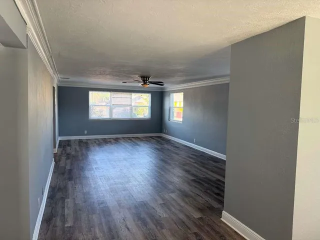 an empty room with wooden floor and windows