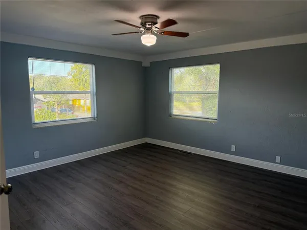 a view of an empty room with wooden floor and a window