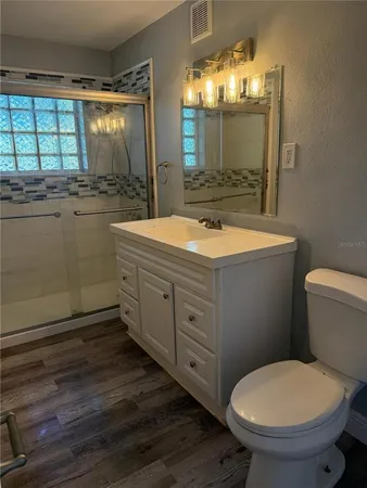 a bathroom with a granite countertop toilet a sink and a mirror