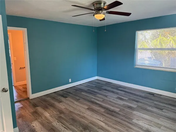 an empty room with a window and wooden floor