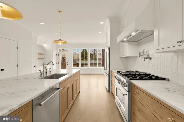 a kitchen with stainless steel appliances granite countertop a sink a stove and a wooden floors