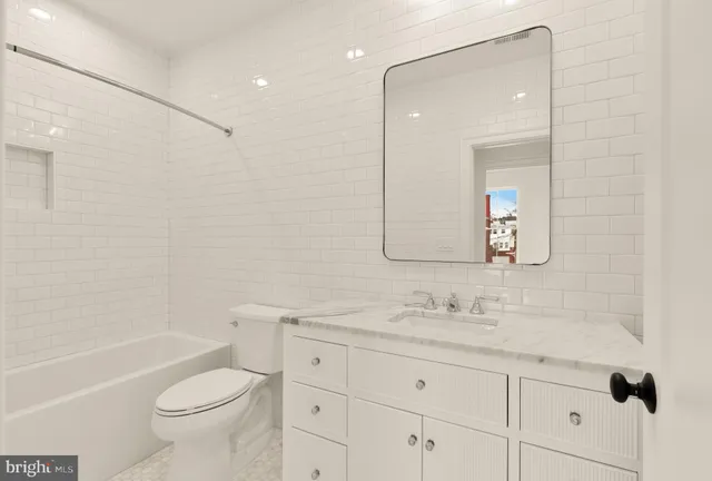 a bathroom with a granite countertop toilet a sink and a bathtub