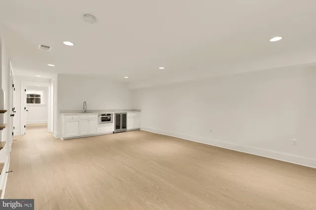 an empty room with kitchen view and a refrigerator