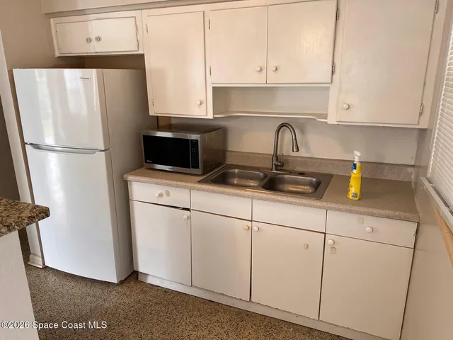 a kitchen with stainless steel appliances a refrigerator a sink a stove and white cabinets