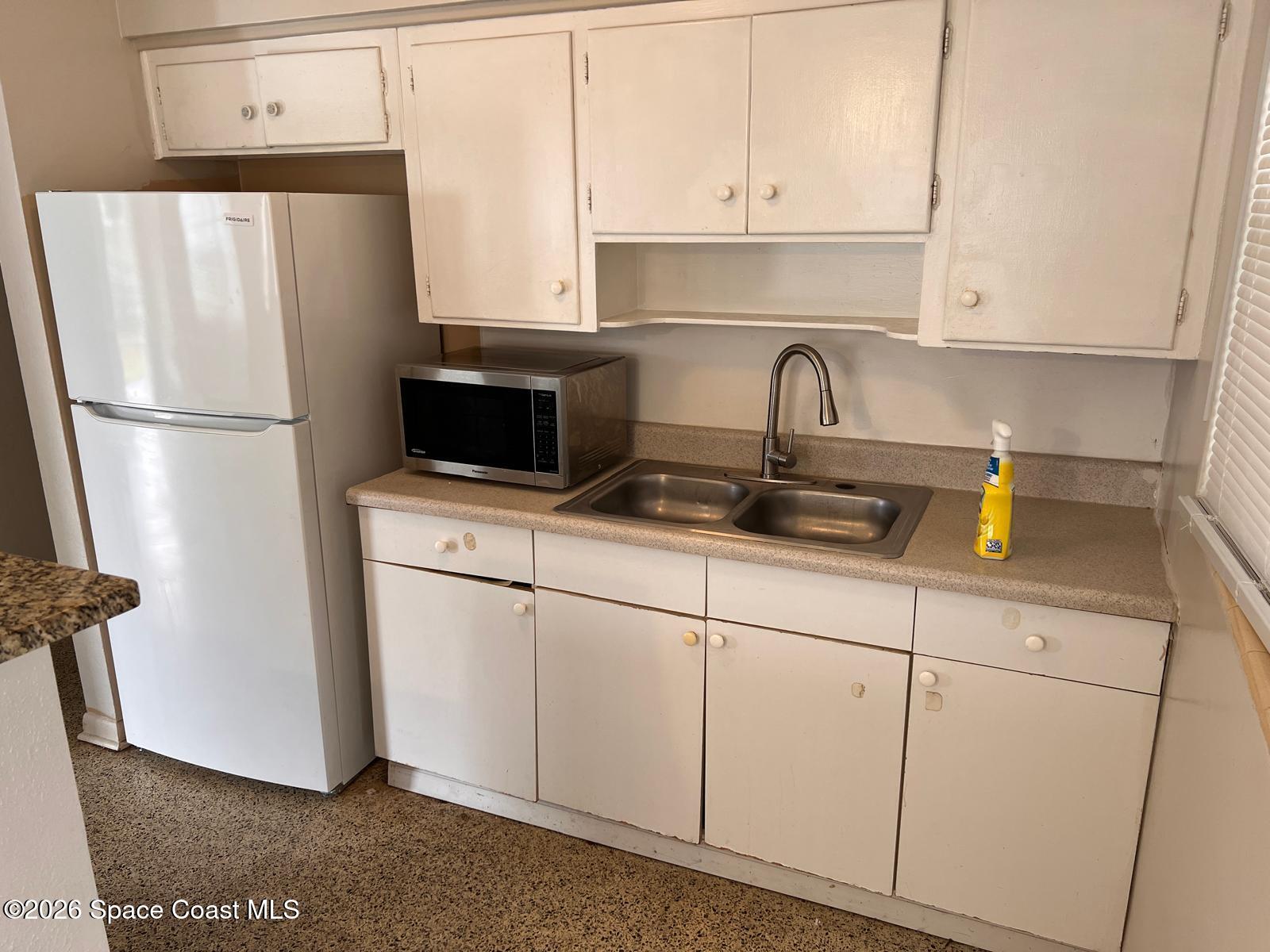 1040 Croton Road Melbourne, FL 32935 - Photo 5 of 10 a kitchen with stainless steel appliances a refrigerator a sink a stove and white cabinets