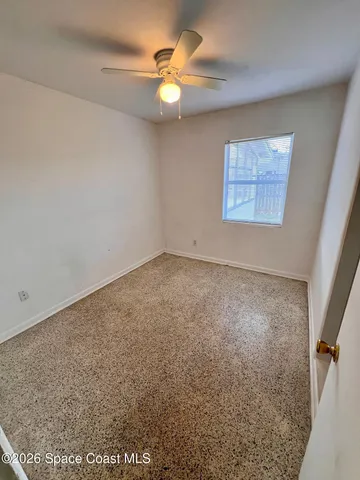 an empty room with a fan & a window