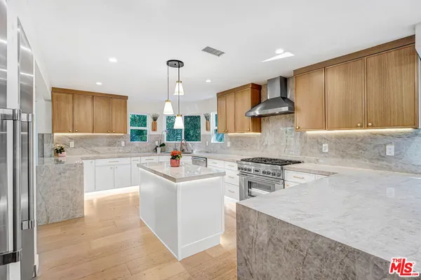 a kitchen with stainless steel appliances granite countertop a sink stove refrigerator and cabinets