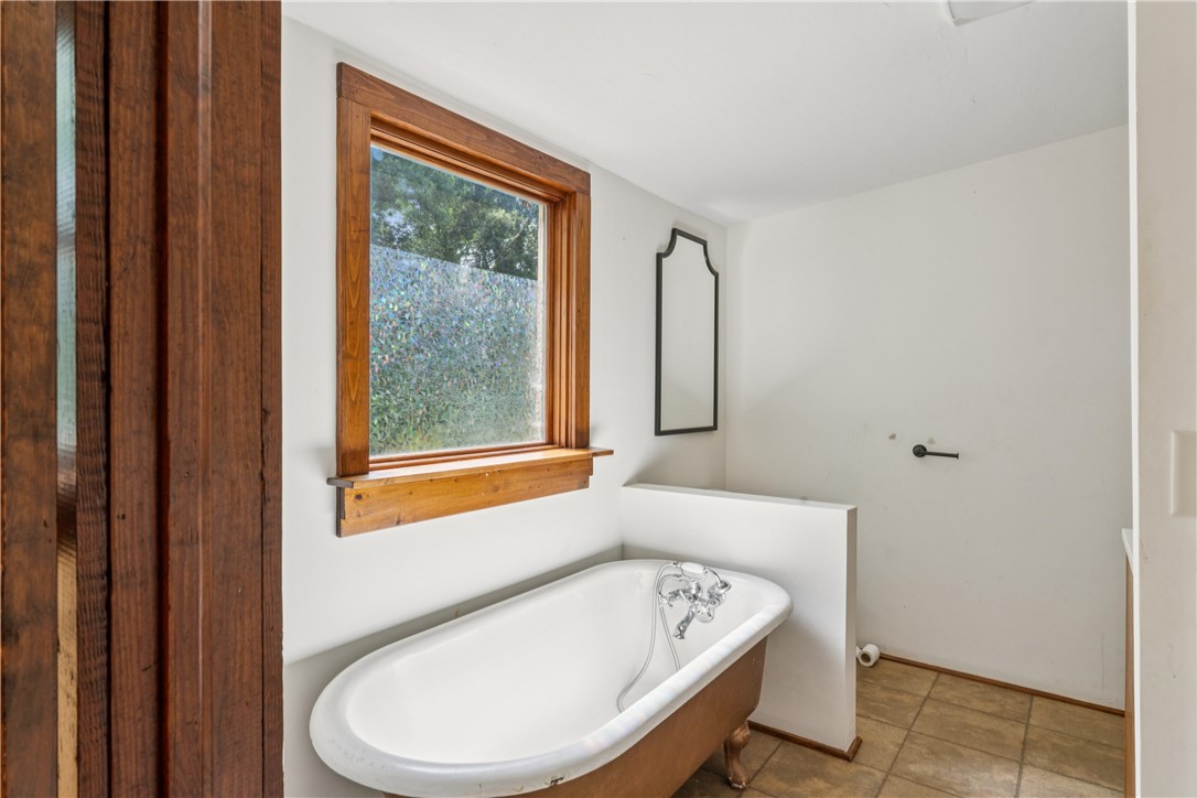 321 South Pine Street Walhalla, SC 29691 - Photo 25 of 32 A well-lit bathroom features a classic clawfoot tub, wood window trim, and tiled flooring.