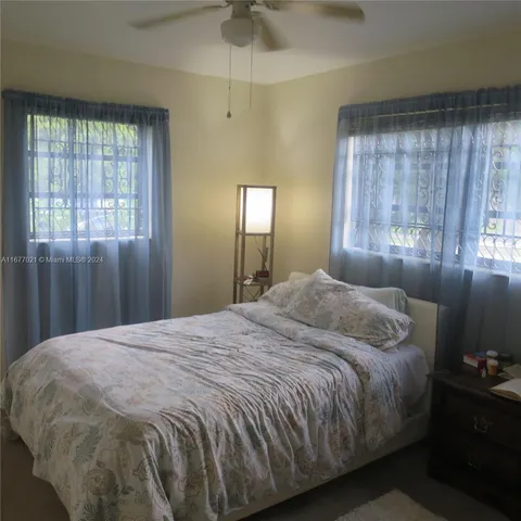 a large bed sitting in a bedroom next to a window and a chandelier