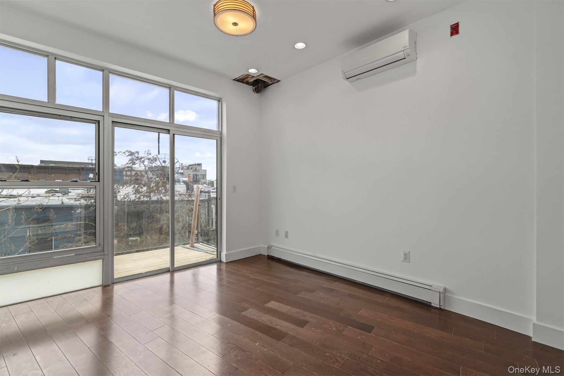 44-46 Decatur Street Brooklyn, NY 11216 - Photo 42 of 50 Empty room featuring a baseboard heating unit, dark wood-style floors, an AC wall unit, and recessed lighting