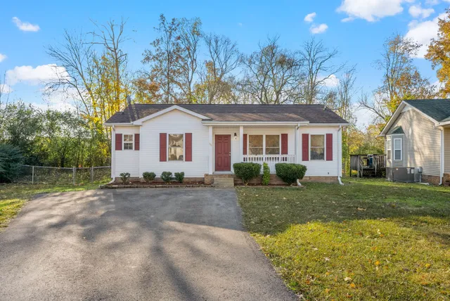 a view of a yard in front of a house with a large tree