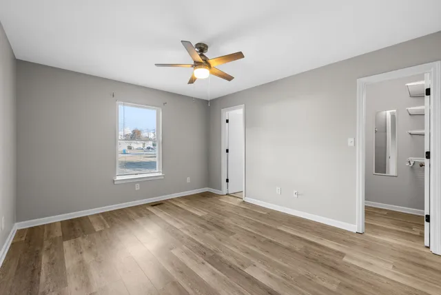 a view of empty room with wooden floor and fan