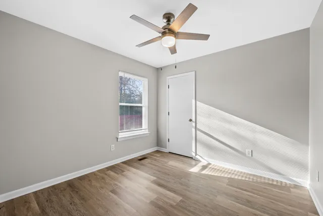 an empty room with a ceiling fan and window