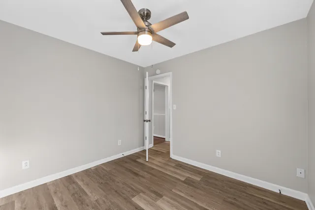 an empty room with wooden floor and ceiling fan