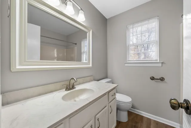 a bathroom with a toilet a sink a mirror and a window