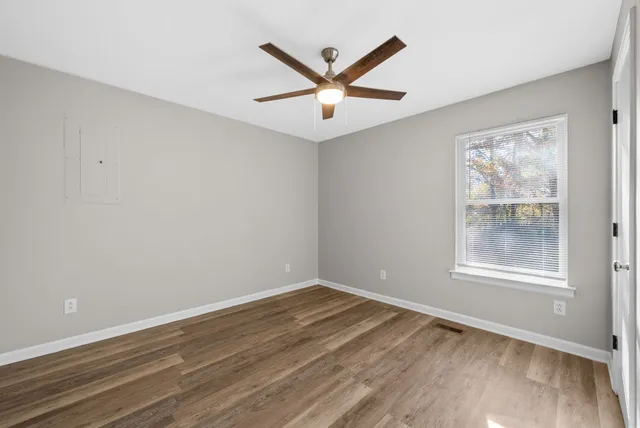 a view of empty room with wooden floor and ceiling fan