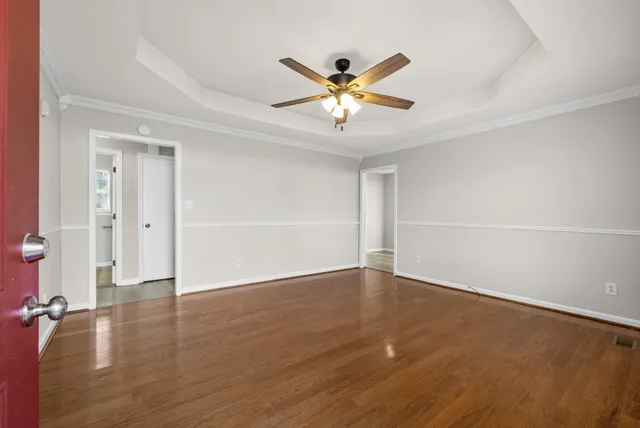 an empty room with wooden floor closet and windows