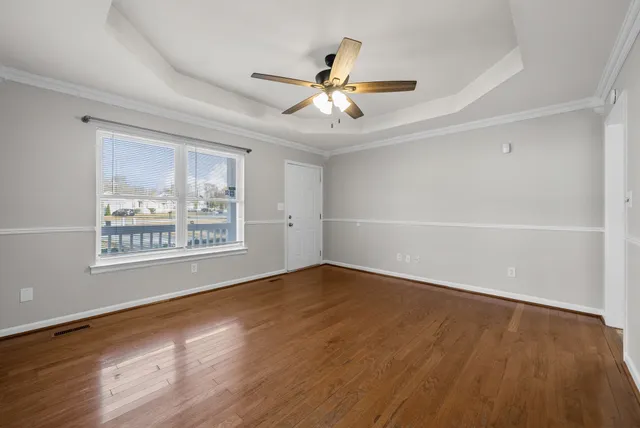 a view of an empty room with a window and wooden floor