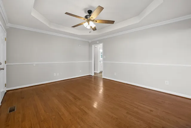 an empty room with wooden floor and a ceiling fan