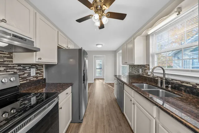 a kitchen with granite countertop a sink stainless steel appliances and cabinets