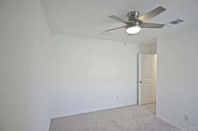 an empty room with a window and a fan