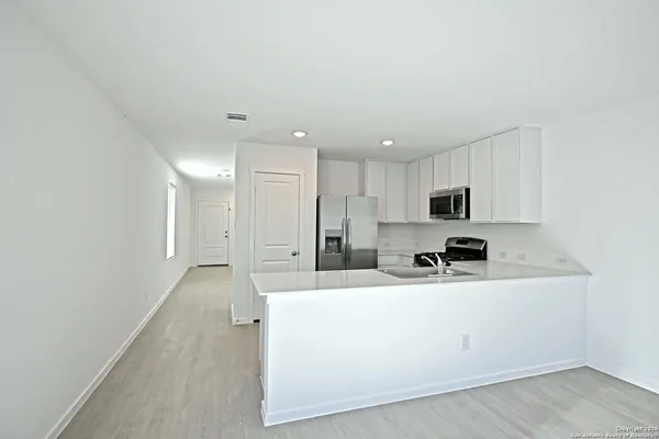 a kitchen with stainless steel appliances a sink a stove a refrigerator with white cabinets