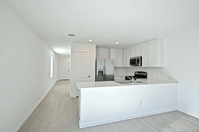 a kitchen with stainless steel appliances a sink a stove a refrigerator with white cabinets