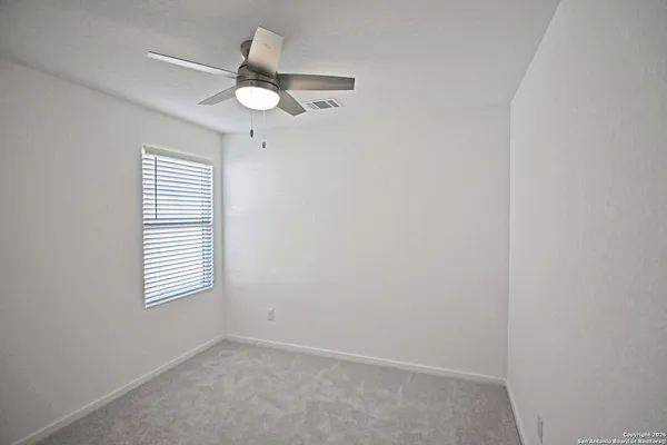 an empty room with a window and a ceiling fan