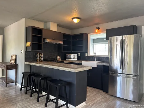 a kitchen with stainless steel appliances granite countertop a table chairs refrigerator and sink