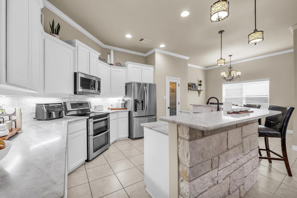 910 Springdale Lane Lorena, TX 76655 - Photo 9 of 39 Kitchen featuring white cabinetry with crown molding, stainless steel appliances, and under-cabinet lighting