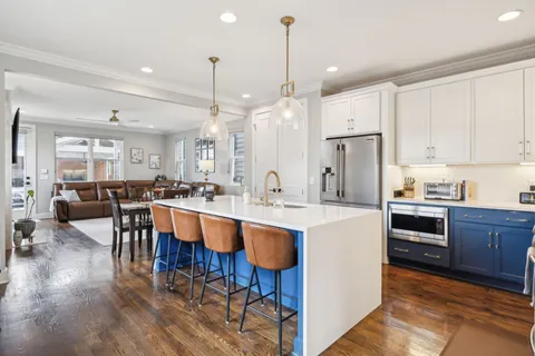 a large kitchen with cabinets chairs and refrigerator
