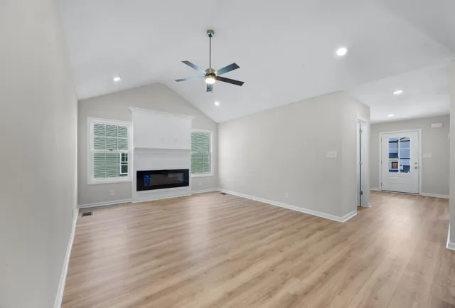 an empty room with wooden floor fireplace and windows
