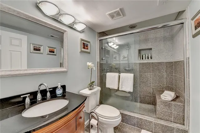 a bathroom with a granite countertop sink mirror vanity and toilet