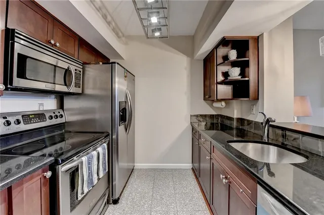 a kitchen with stainless steel appliances granite countertop a sink a stove and a refrigerator