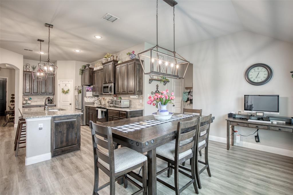 211 Rees Avenue Godley, TX 76044 - Photo 9 of 18 a kitchen with a table chairs refrigerator and wooden floor