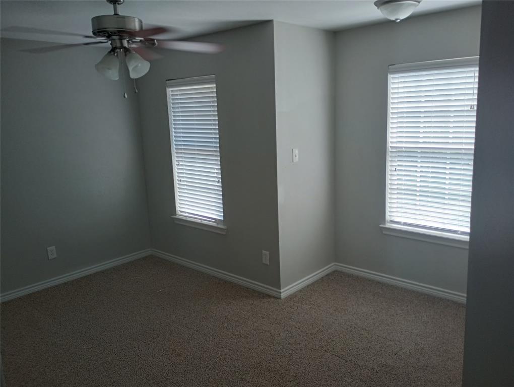2004 Pecan Street, Unit G Commerce, TX 75428 - Photo 9 of 10 Carpeted bedroom featuring plenty of natural light and ceiling fan