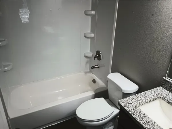 a white toilet and tub sitting next to a bathroom sink
