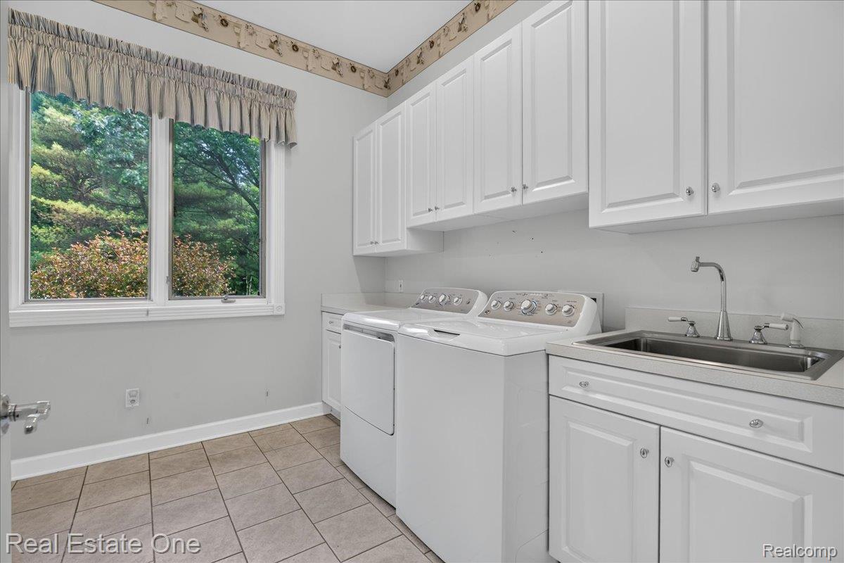 425 Courtney Road Leonard, MI 48367 - Photo 31 of 89 Laundry area featuring a double window, white shaker-style cabinetry, a stainless steel utility sink, and tile flooring