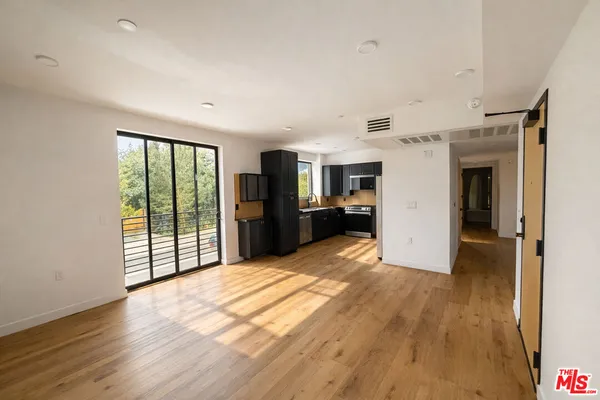 a view of a kitchen with refrigerator and wooden floor
