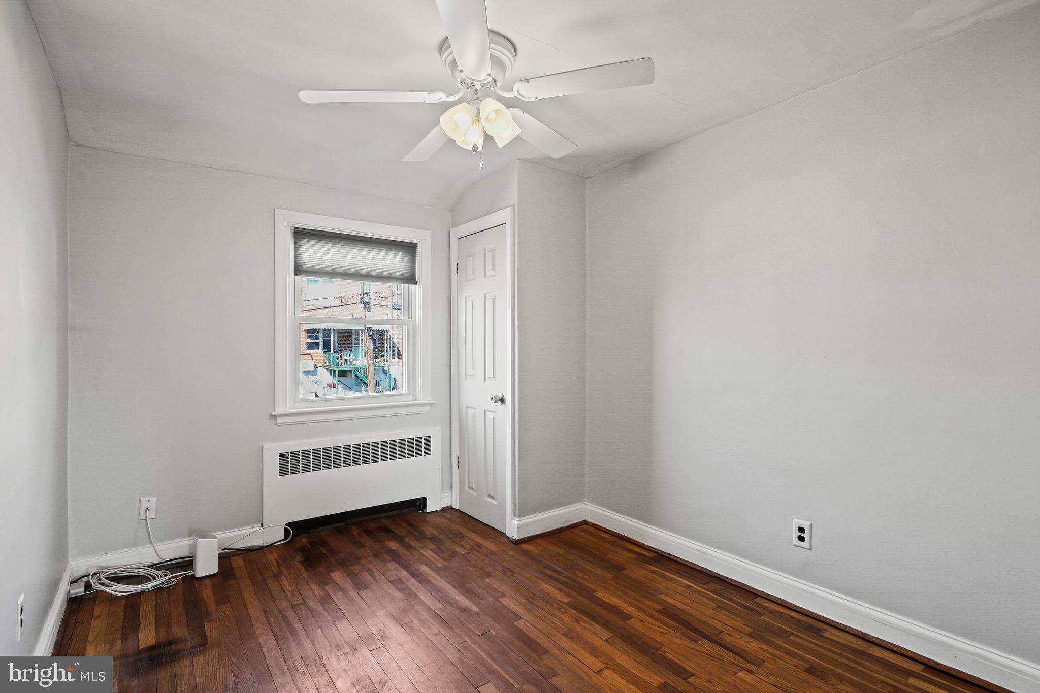 3812 Rexmere Road Baltimore, MD 21218 - Photo 21 of 35 an empty room with wooden floor chandelier fan and windows