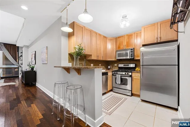 a kitchen with stainless steel appliances kitchen island granite countertop a refrigerator a stove a sink dishwasher and a refrigerator with wooden floor