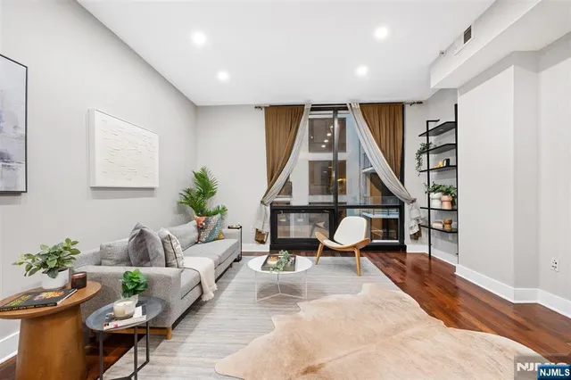 a living room with furniture a rug potted plant and a painting on the wall