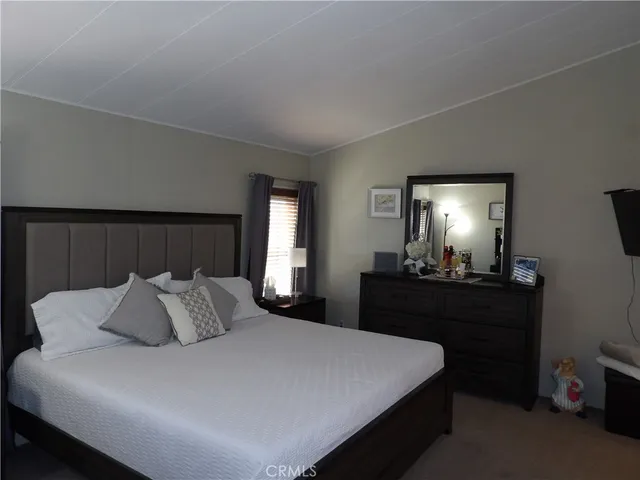 a bedroom with a bed and a lamp on dresser