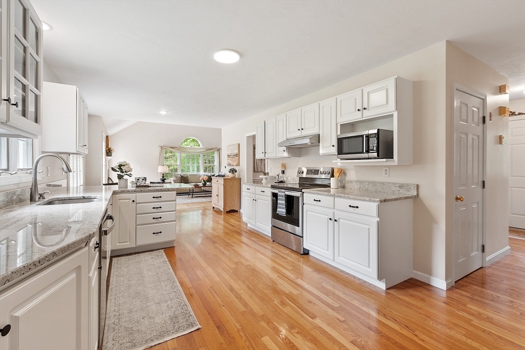 28 Old Harvard Road Boxborough, MA 01719 - Photo 12 of 40 a large kitchen with stainless steel appliances granite countertop a stove top oven a sink a refrigerator and white cabinets with wooden floor