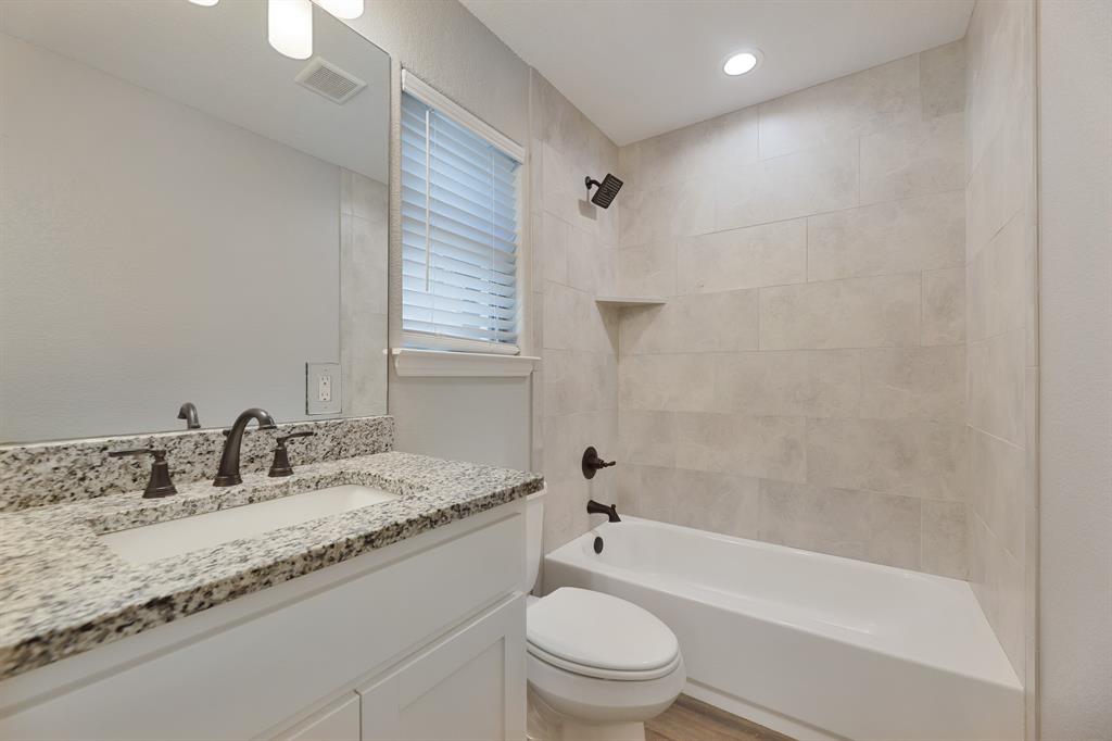 1713 Bronco Road Granbury, TX 76049 - Photo 15 of 23 Bathroom featuring a white vanity with a speckled countertop, undermount sink, and dark bronze fixtures