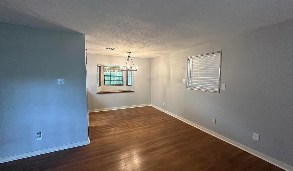 1204 Wilbec Road Memphis, TN 38117 - Photo 2 of 5 Unfurnished room featuring a textured ceiling, dark wood-type flooring, and a chandelier
